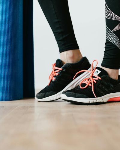 Close-up of a person's athletic shoes on a yoga mat.